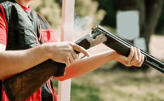 Man opens the shotgun bolt after one shot with smoke