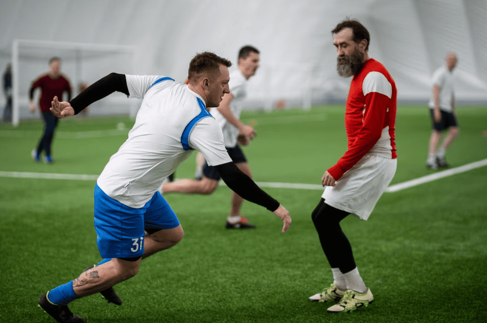 men playing soccer on the field, one in blue shorts, the other in a red t-shirt