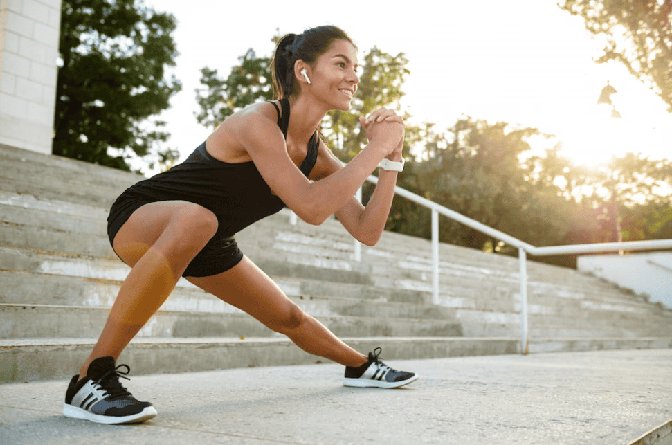 smiling woman doing fitness in earphones, stairs behind her