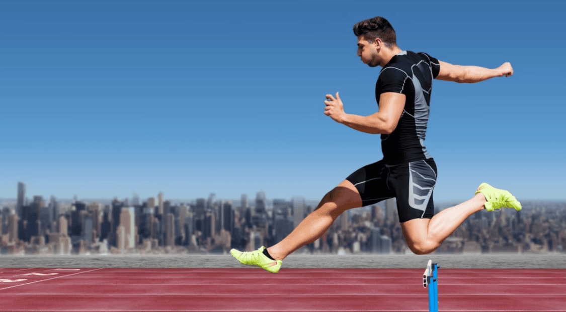 man jumping on track in yellow sneakers and skyscrapers behind