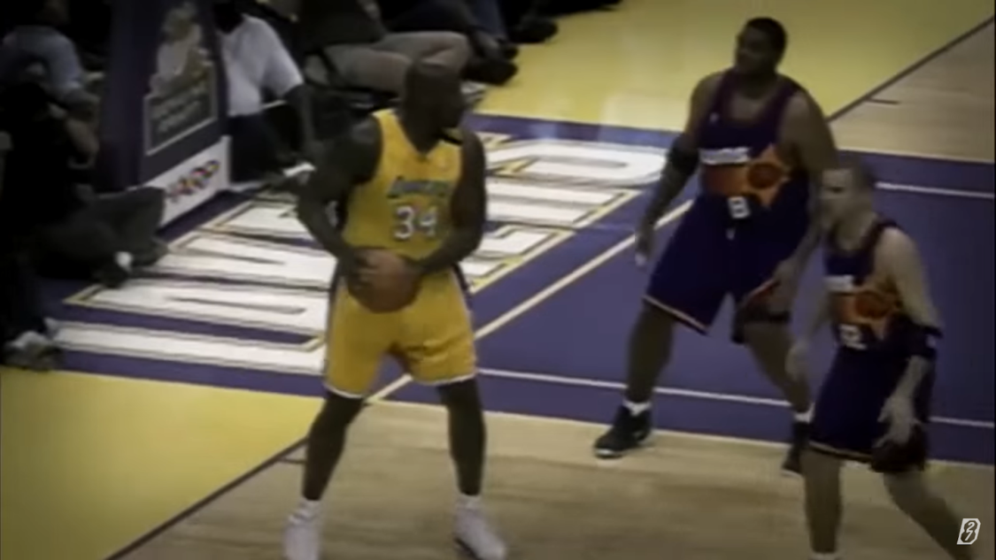 Shaquille O’Neal as a lakers player  holds a basketball ball on a field among others players