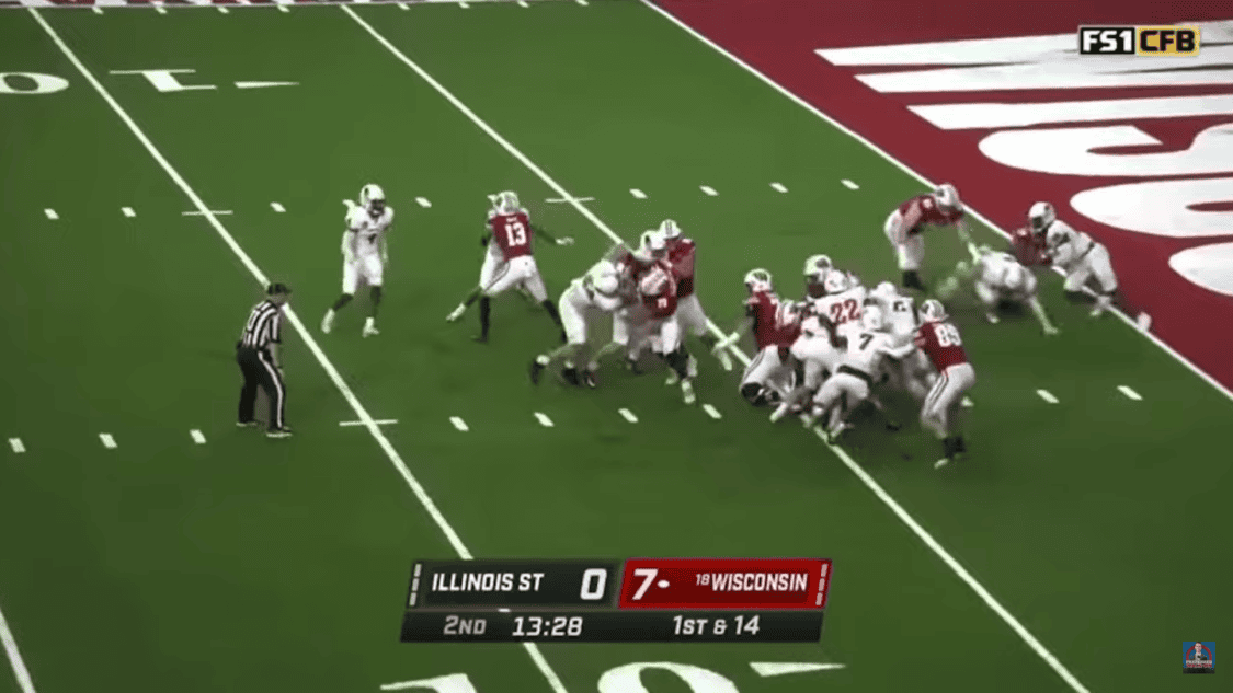 two walk-on football teams on the field during gameplay and a referee observing them