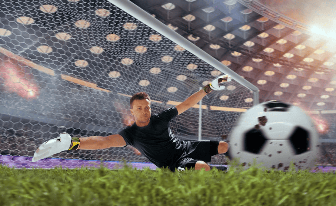 goalkeeper near the football net catching the ball and falling on the grass