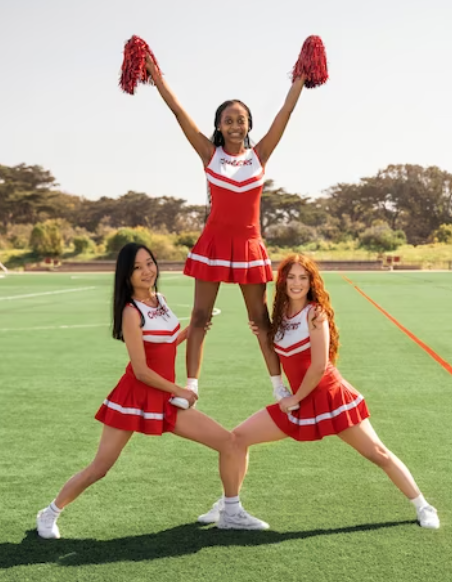 wo cheerleaders in red uniform holding one girl on their legs and smiling